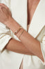 close up of woman's wrist wearing gold cable chain bracelet with seven baguette diamonds alongside another gold bracelet