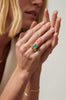 close up of woman wearing Open Bottom Cathedral Bezel set colombian emerald ring with a gold soft knife edge band