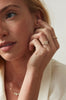 close up of woman wearing gold ring with elongated rose cut oval diamond and round white diamonds alongside other gold jewerlry