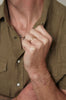 close up of man's hand wearing rounded gold band alongside other gold jewelry