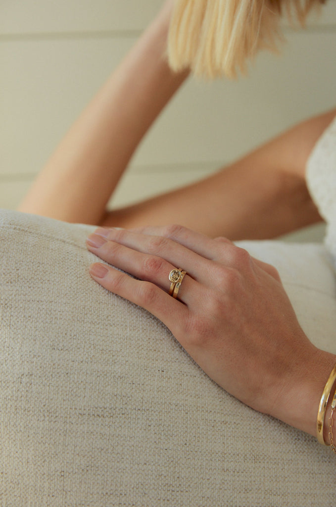 woman wearing yellow gold band with three baguette white diamonds alongside other ring