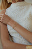 close up of woman wearing gold cuff with rounded edges alongside other gold jewelry