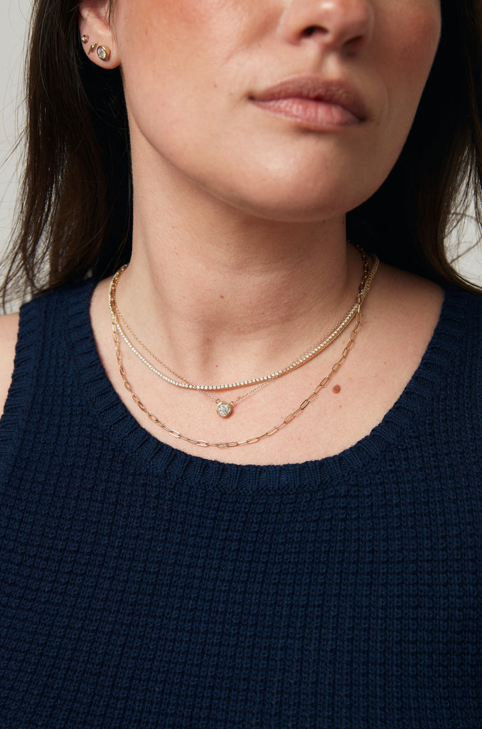 close up of woman wearing gold cable link chain alongside other gold jewelry