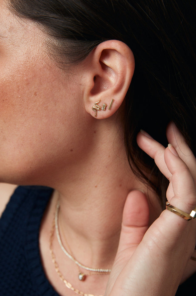 woman wearing gold serpent shaped stud alongside other gold earrings