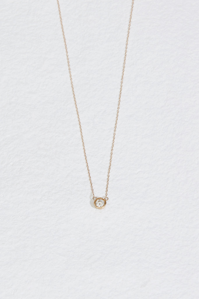 gold necklace with bezel set round white diamond