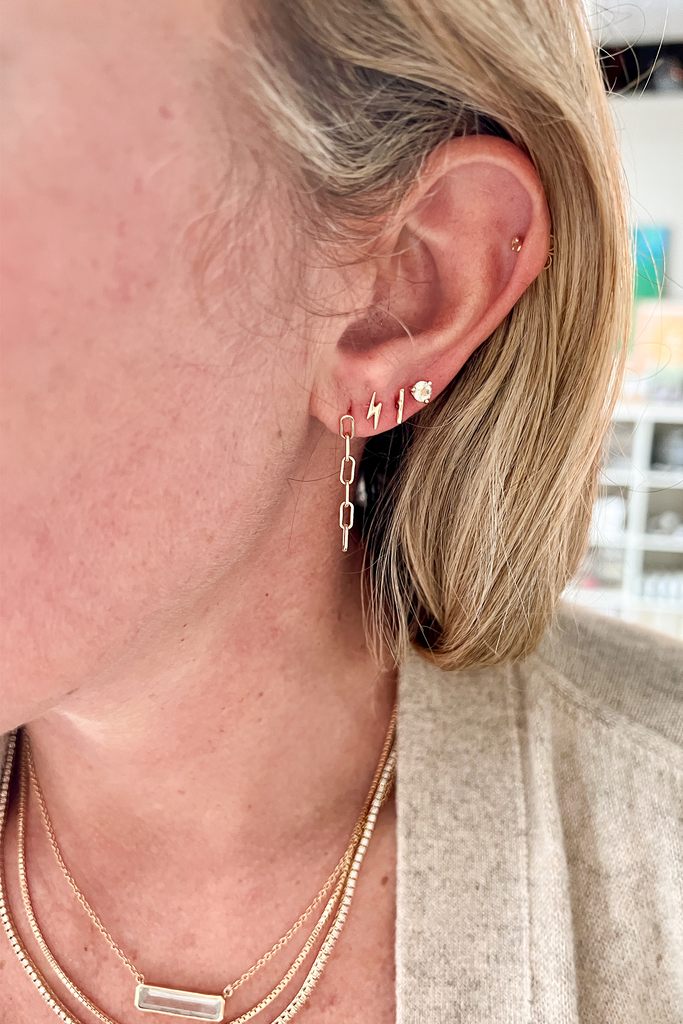 close up of woman wearing cable link chain drop stud alongside other earrings