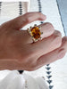 close up of hand wearing gold ring with xl prongs and citrine