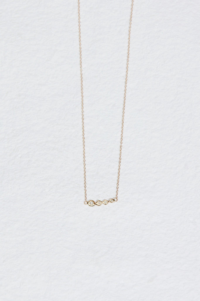 gold necklace with four bezel set round white diamonds