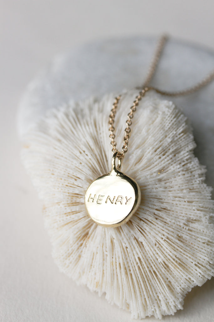 close up of gold necklace with engraved name disc