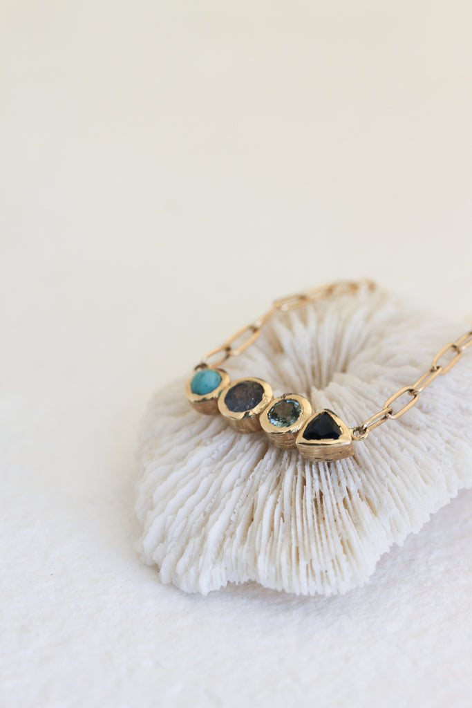 gold necklace with round turquoise cabochon,  round labradorite, round blue topaz, and trillion blue sapphire