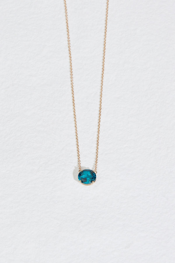 gold necklace with oval blue topaz