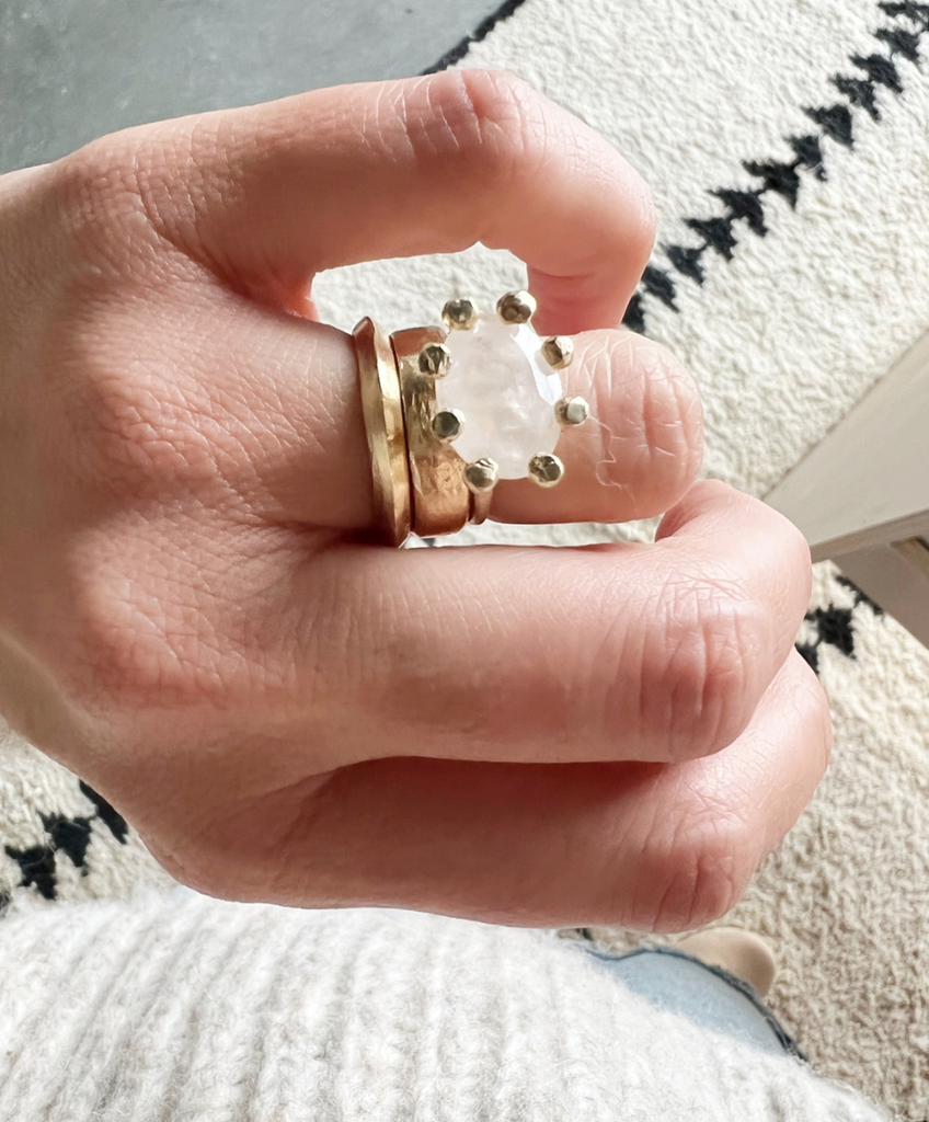 close up of hand wearing gold ring with xl prongs and moonstone
