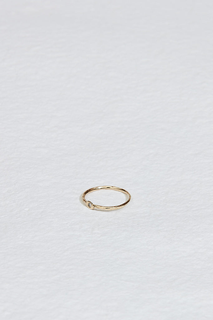 side view of thin gold textured band with round white diamond