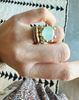 close up of hand wearing gold ring with xl prongs and chalcedony