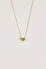 close up of gold necklace with oval peridot