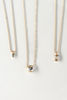 close up of gold ball chain necklace with partial bezel set emerald cut diamond alongside other diamond necklaces