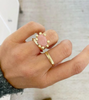 close up of hand wearing gold ring with xl prongs and pink opal