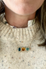 close up of woman wearing three stone bezel set necklace on cable chain