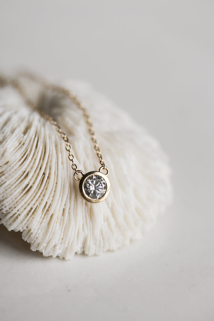 close up of gold necklace with bezel set round salt and pepper diamond