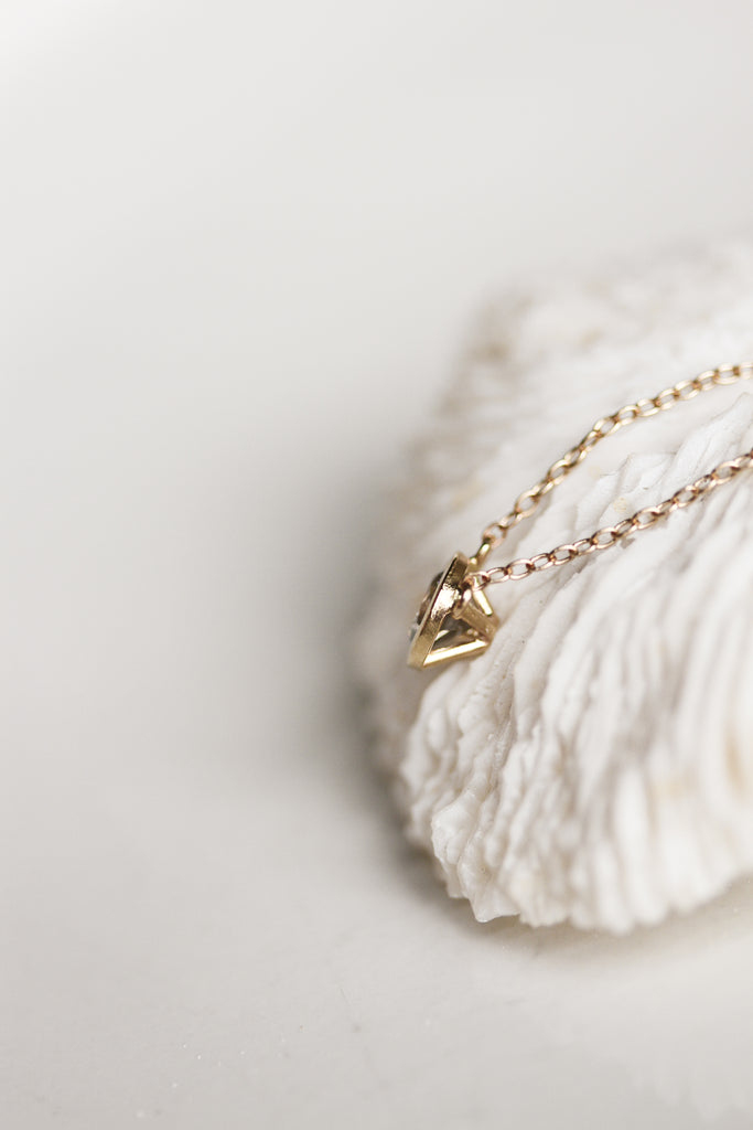 close up side view of gold necklace with bezel set round salt and pepper diamond