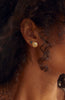 close up of woman wearing gold disc stud with round white diamond alongside other gold earrings