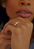 close up of woman wearing gold ring with three bezel set round white diamonds