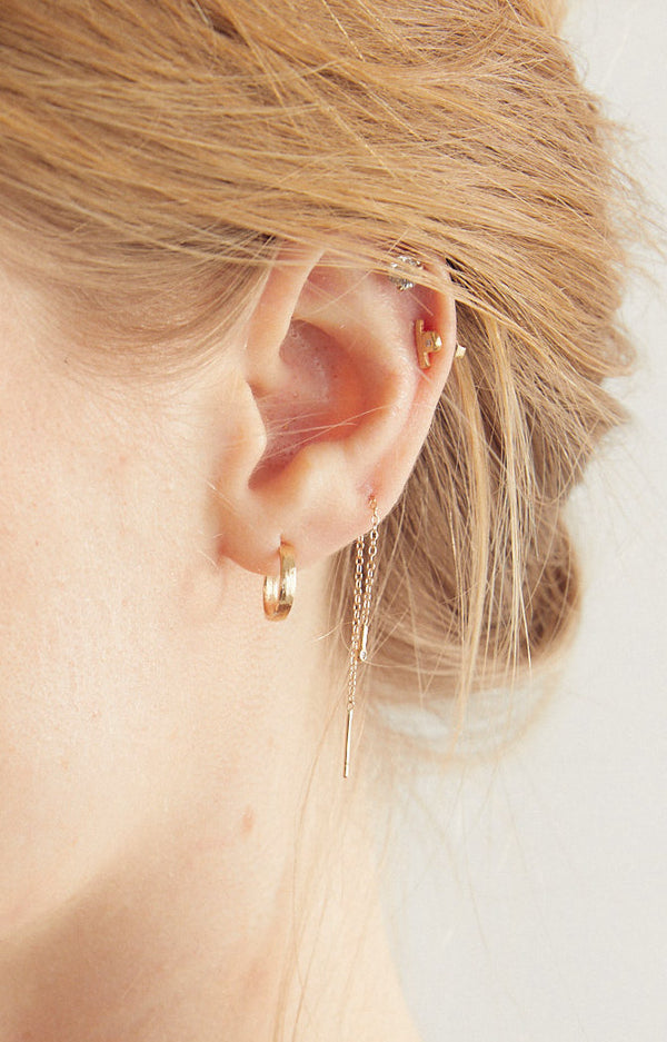 woman wearing gold stud with slate bar and off set bezel set diamond among other gold earrings