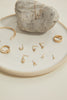 gold ring with "BIG LOVE" engraved plate on plate alongside other gold jewelry