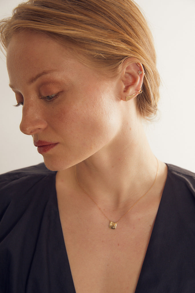 woman wearing gold spiral earring alongside other gold earrings