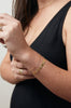 close up of woman wearing gold cable link chain bracelet alongside other gold jewelry