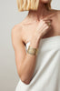 woman wearing thick gold cuff bracelet alongside other gold jewelry