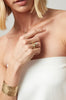 close up of woman wearing gold ring with bezel set oval white diamond
