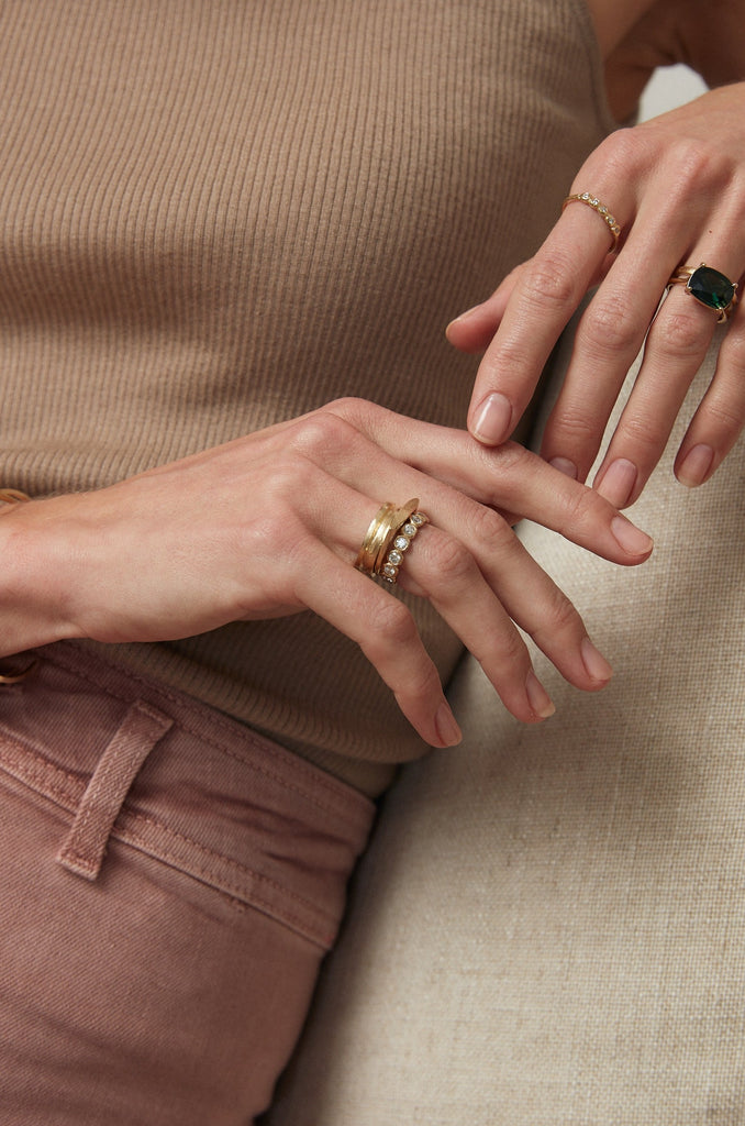 close up of woman wearing gold ring with angular face alongside other gold rings