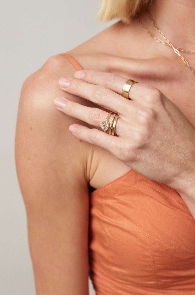 woman wearing gold six prong ring with old euro cut round diamond alongside other gold rings
