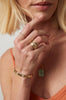 woman wearing gold moderately textured band with notch in center alongside other gold jewelry