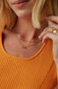 close up of woman wearing gold cable link chain alongside other gold jewelry