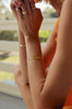 woman wearing gold cable chain bracelet alongside two bracelets and three gold rings
