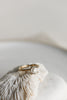 close up of gold four prong ring with old european cut round white diamond