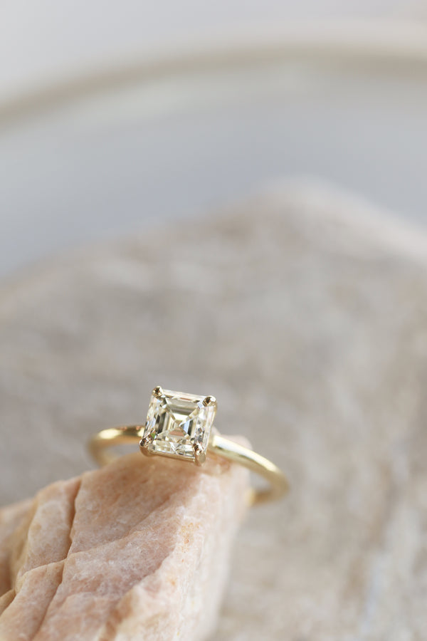 close up of four prong gold ring with asscher cut white diamond