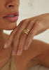 woman wearing thin gold band with straight sides alongside other gold rings