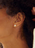 close up of woman wearing three prong round white diamond stud