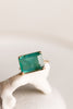 close up of gold four prong ring with emerald cut zambian emerald