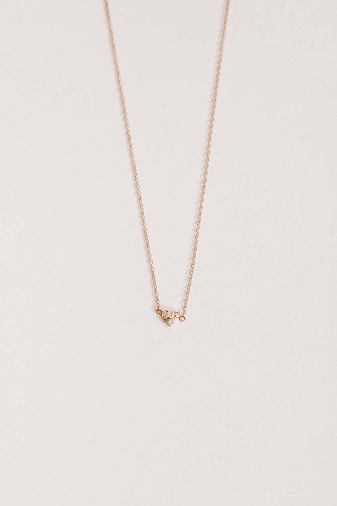 gold necklace with cluster of three bezel set round white diamonds