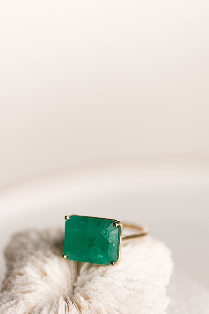 side view of gold four prong ring with emerald cut emerald