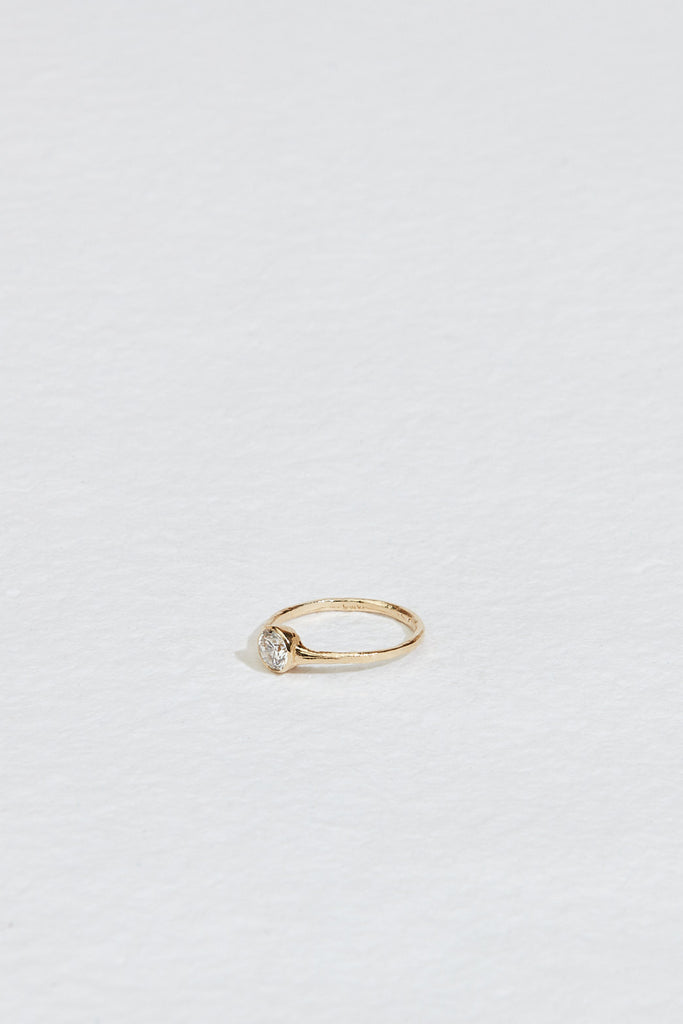 side view of gold ring with bezel set round white diamond