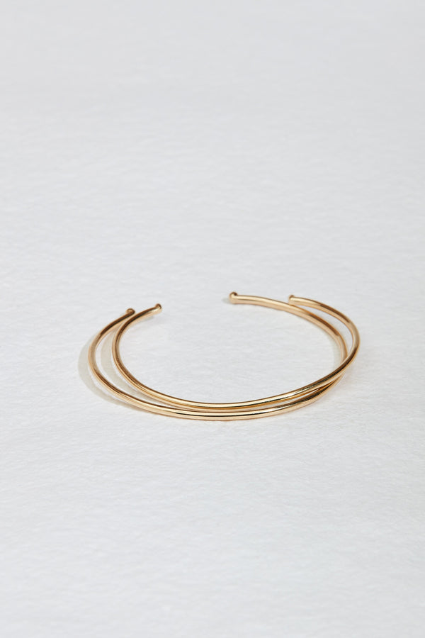 close up of two thin gold cuffs with knotted ends