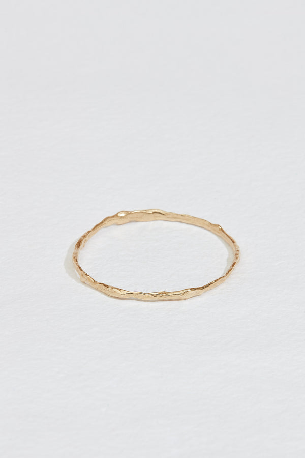 close up of gold bangle with branch-like finish