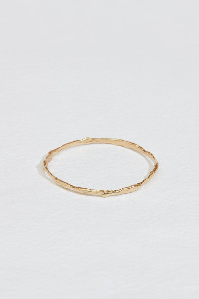 close up of gold bangle with branch-like finish