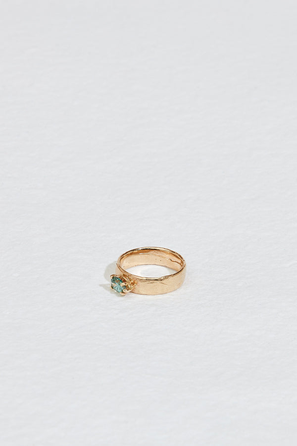 side view of wide gold band with blue green pear diamond
