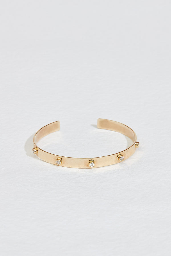 close up of gold cuff bracelet studded with round diamonds